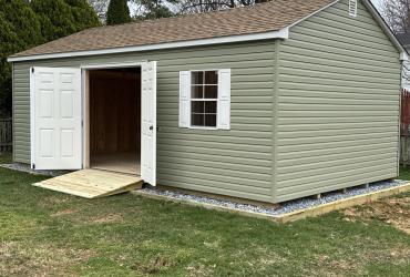 Sage colored shed with doors open, photo taken at a side angle.