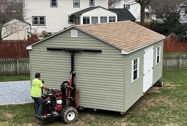 Sage colored shed being delivered to the foundation.