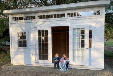 White studio shed with double doors in front.