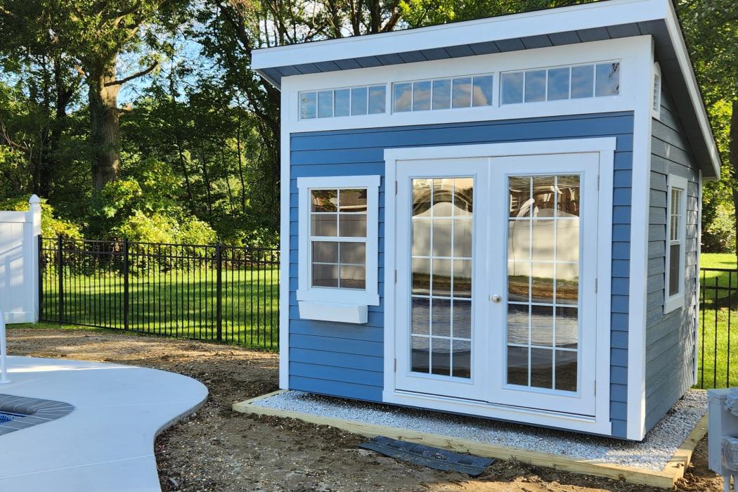 Backyard Studio Shed in Light Blue next to pool.