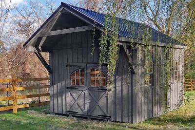 High sided classic mini barn with black metal roof and large front porch